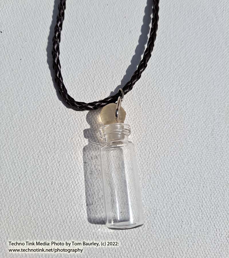 Glass vial with stopper pendant on brown braided leather cord necklace